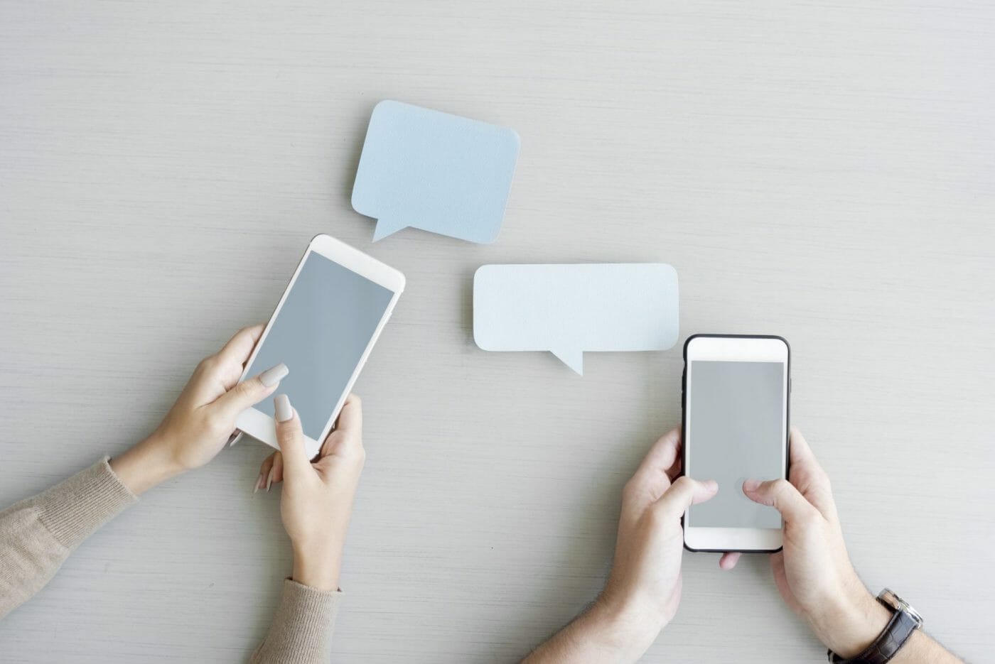Hands holding mobile phones featuring speech bubbles