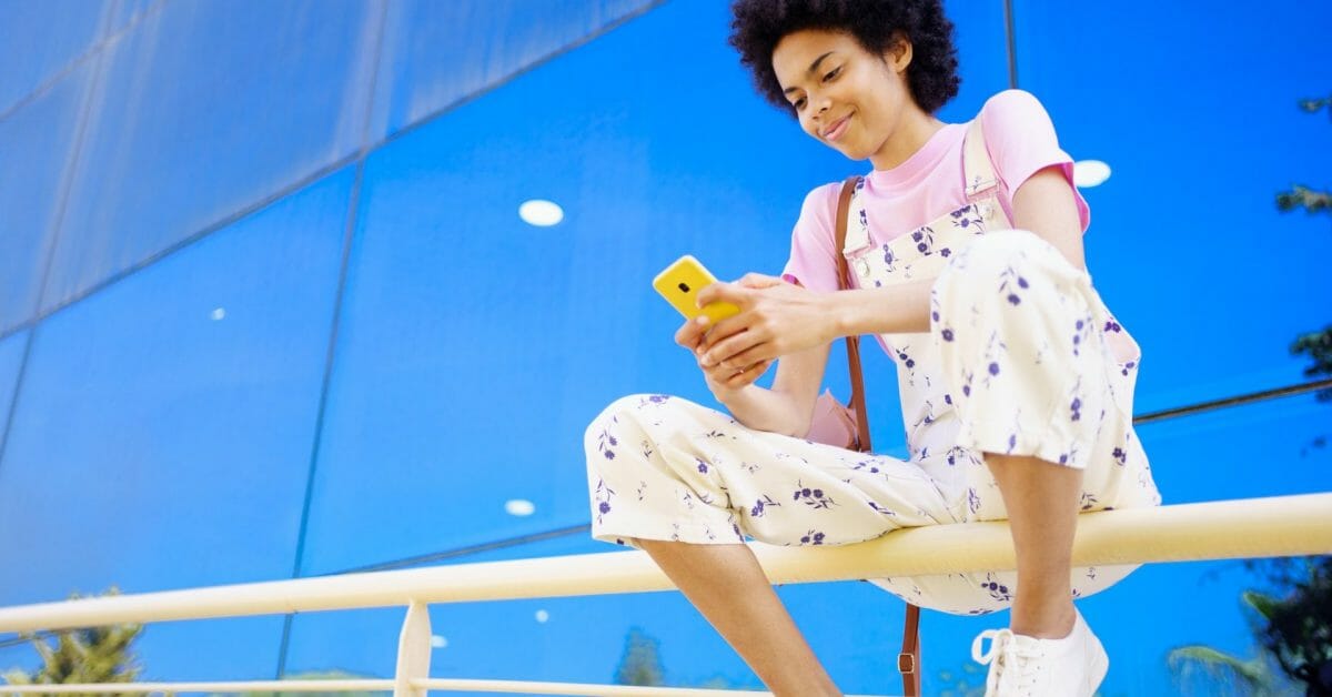 Content black woman texting message on fence