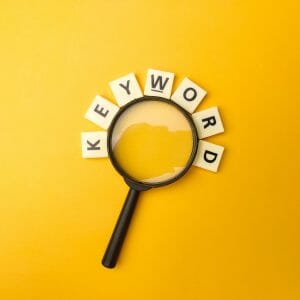 Magnifying glass and toys word with the word KEYWORD on yellow background
