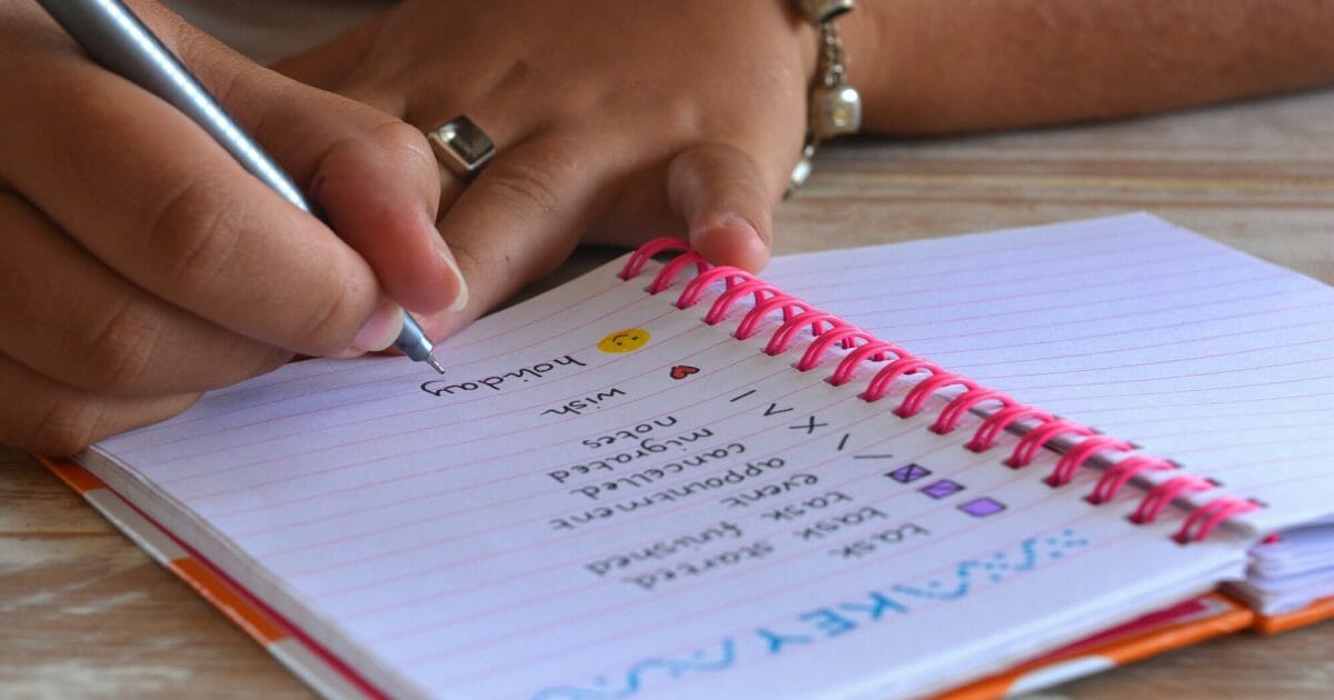 Bullet journal open to key bullet points, with hand holding pen, focus on nib and the word holidays