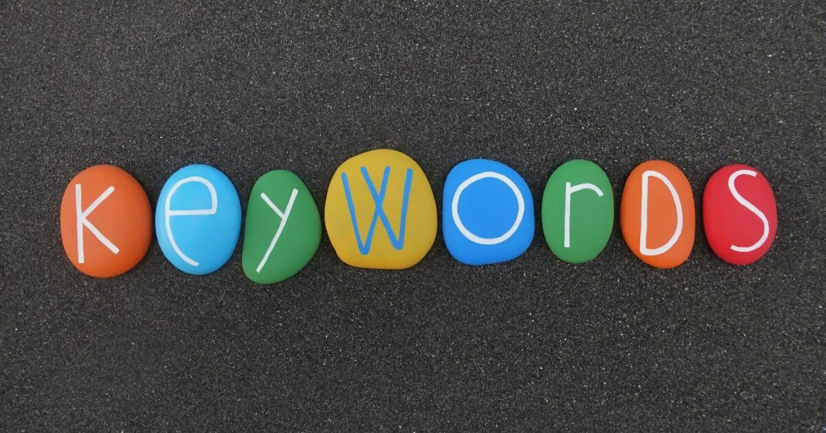 Keywords text composed with multi colored stones over black volcanic sand