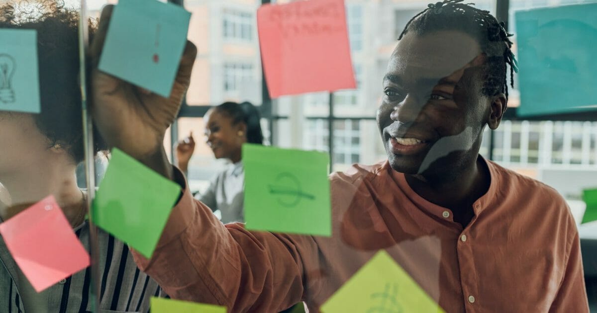 Multiracial team at work writing ideas on sticky notes on the glass wall