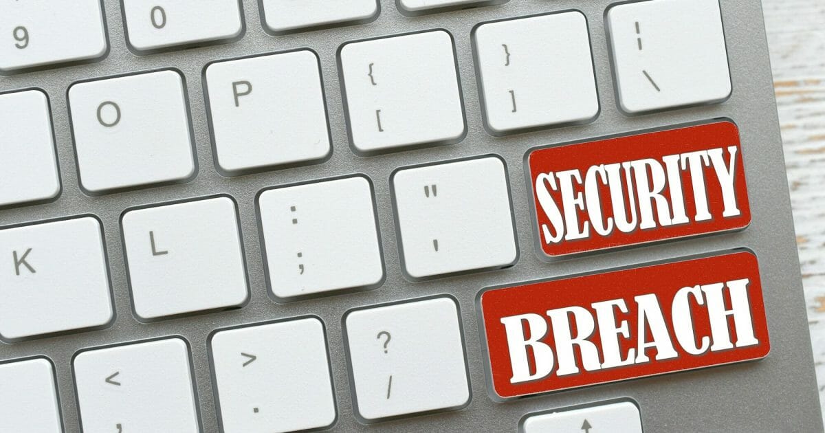 White computer keyboard with red keys that say Security Breach, online dangers Concept hacked