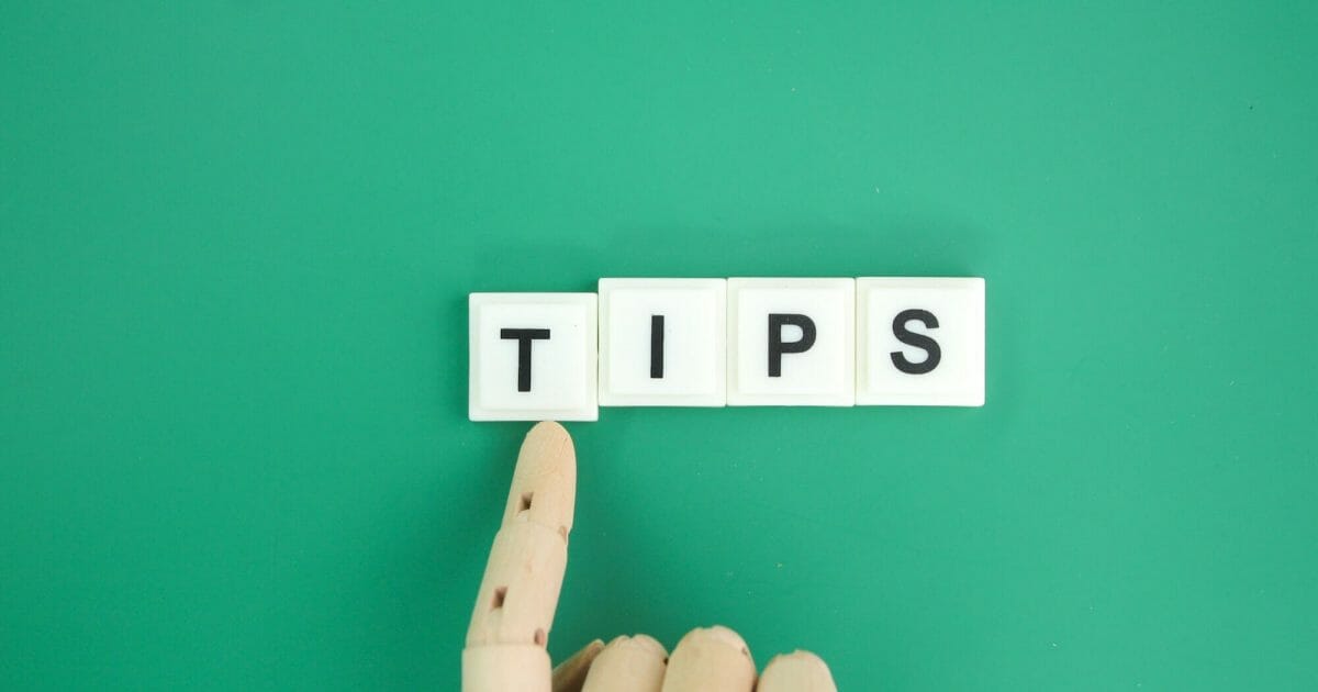 wooden hand pushing the letter T with the word TIPS.