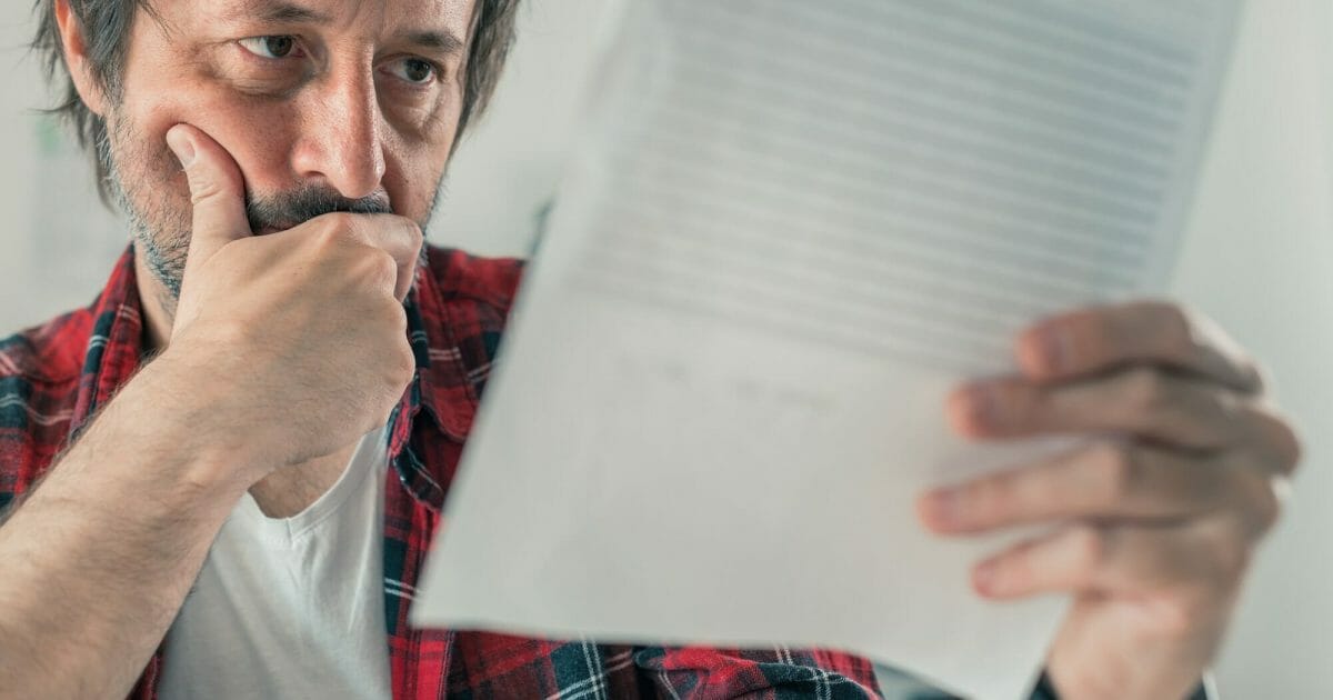 Worried freelancer reading business contract and terms of service document papers