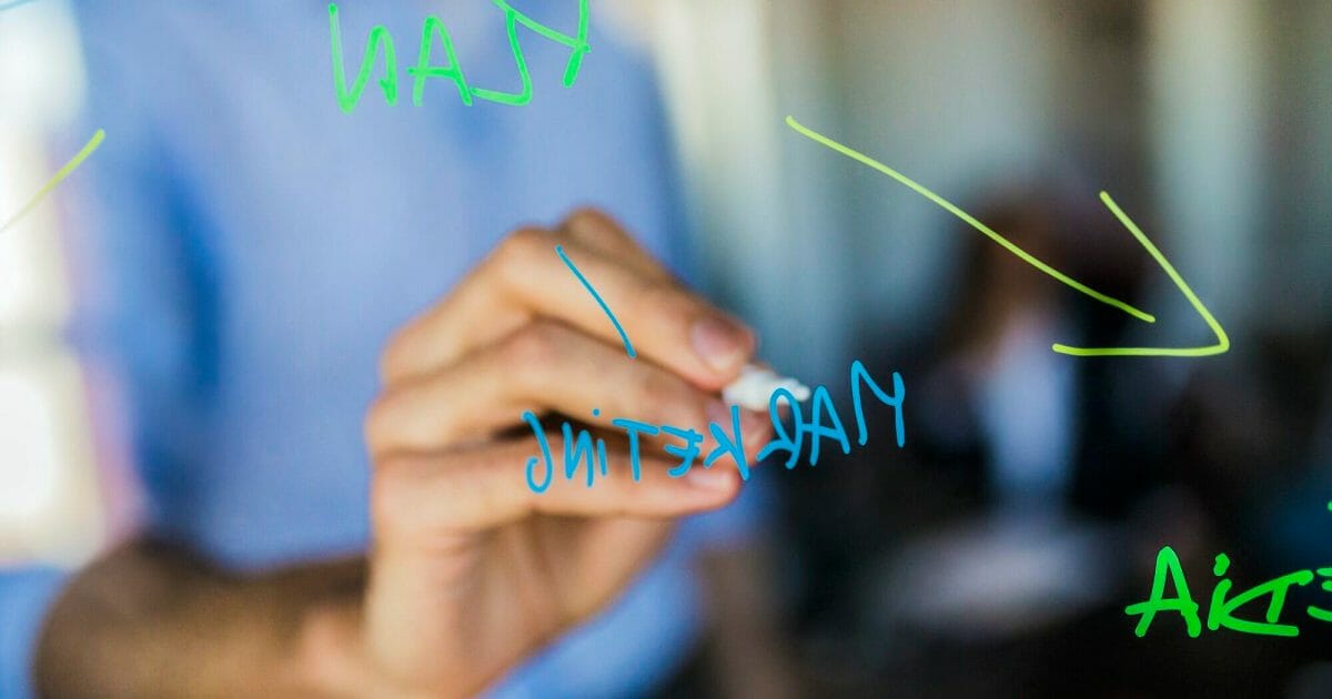 Businessman writing on glass wall